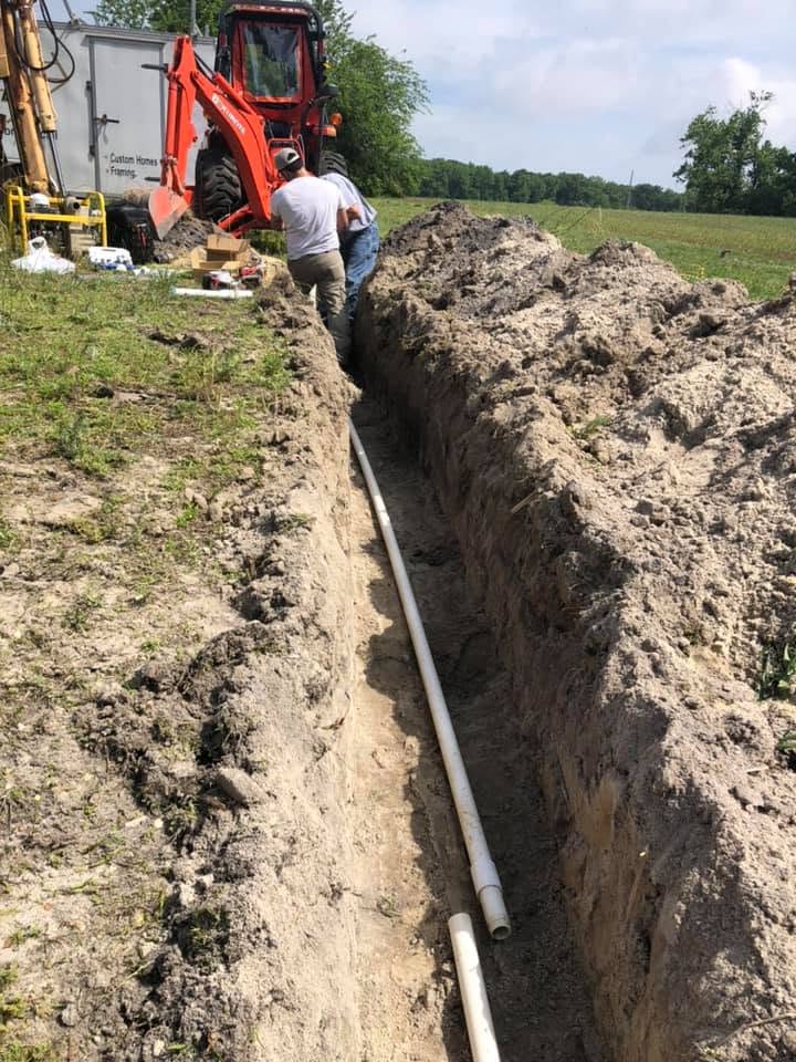 C & B Plumbing crew laying new underground water line pipe in an open trench
