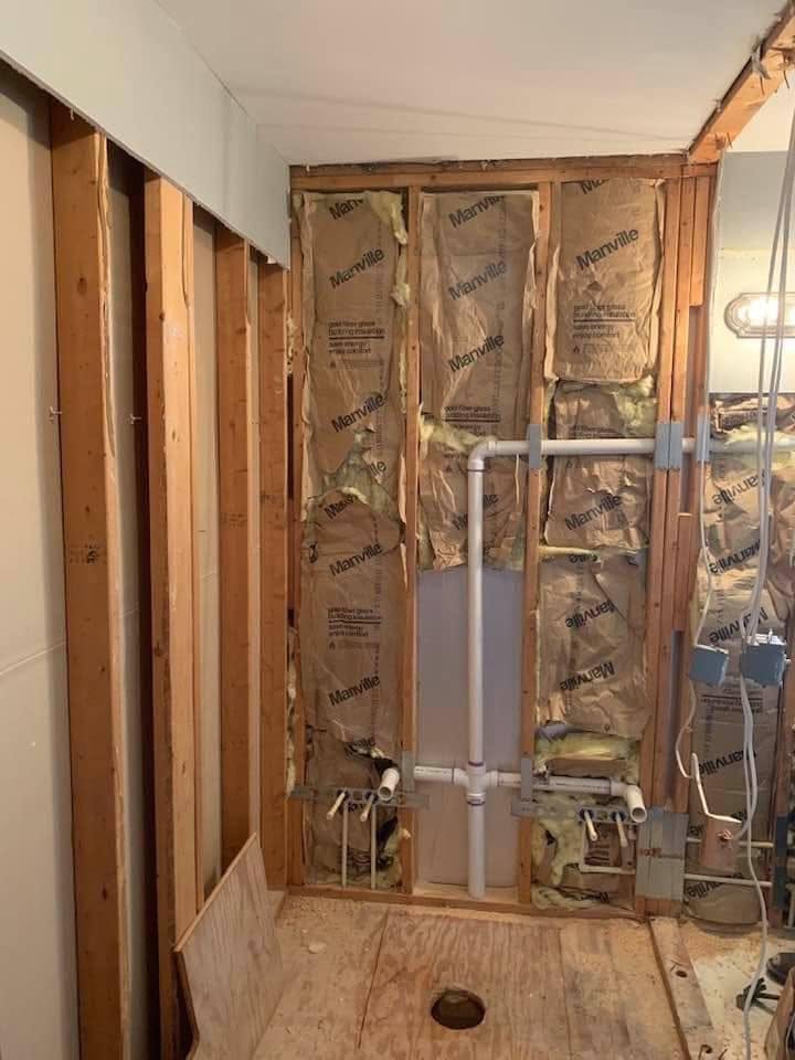 New PVC drain and vent rough-in plumbing inside an open bathroom wall